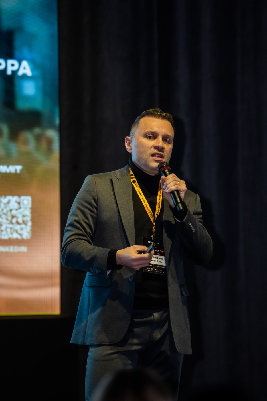 Gustavo no palco do Supply Summit 2026 com a plateia em primeiro plano
