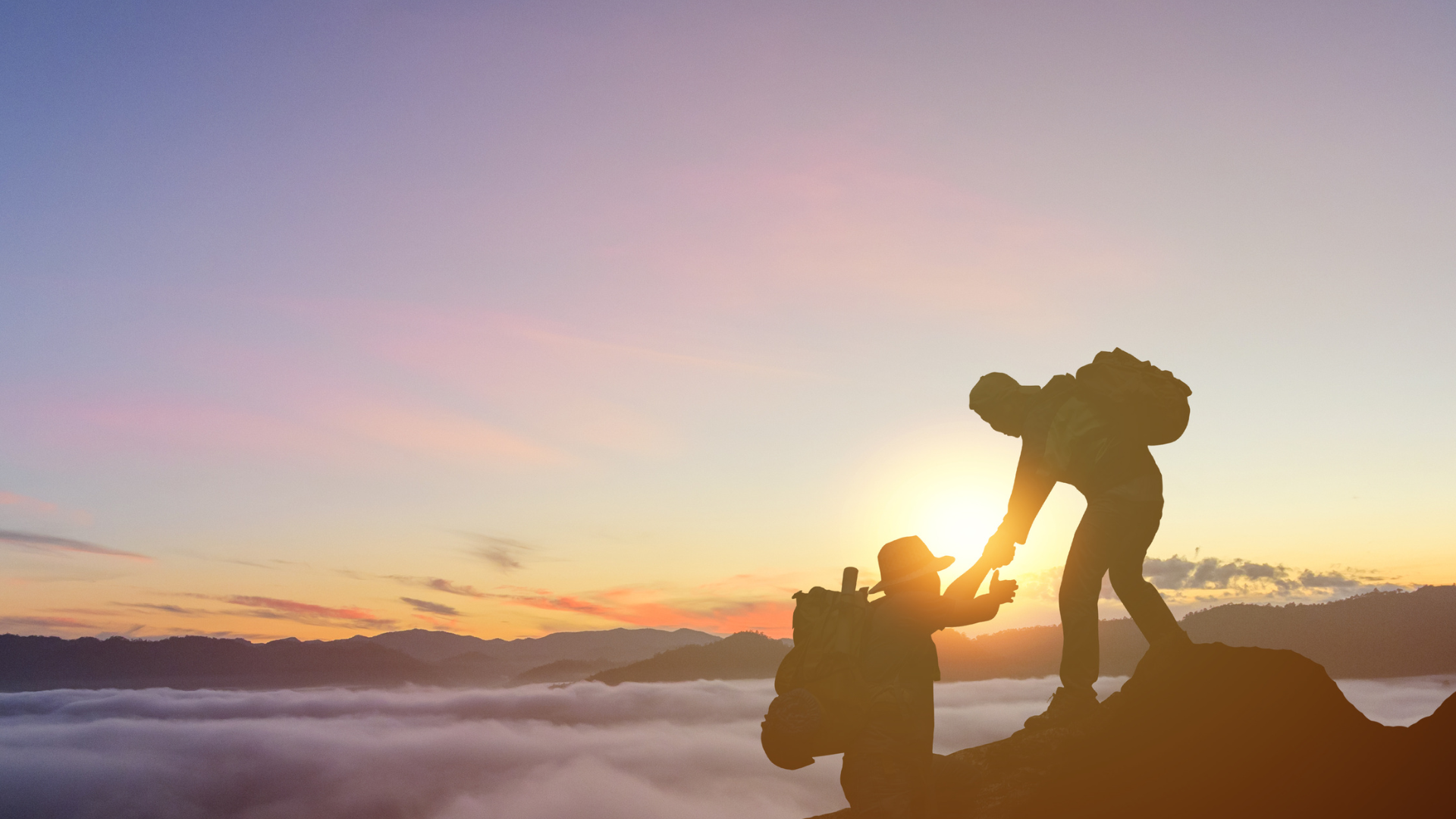 Dois alpinistas no alto da montanha ao amanhecer, um puxando o outro para cima